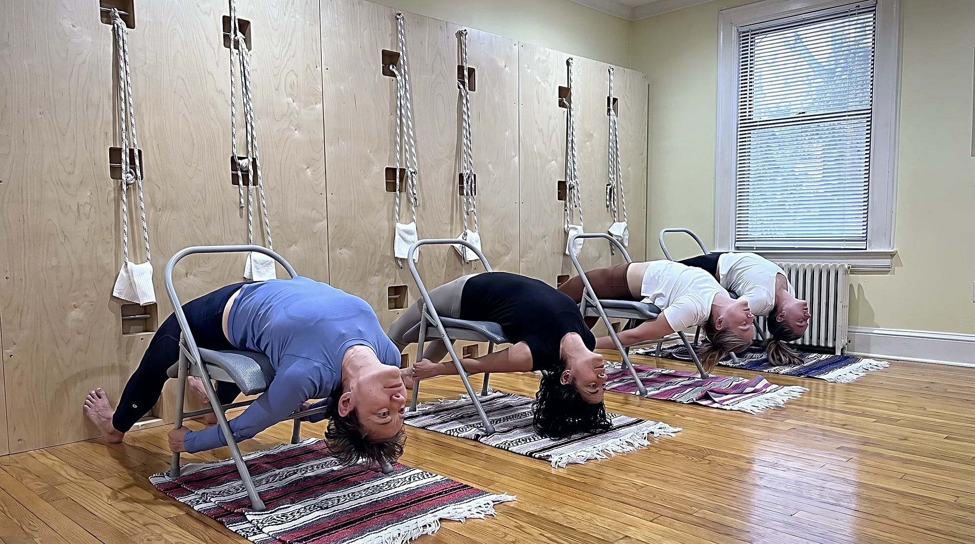 A yoga instructor showing an older student a seated modification using a block and a folded blanket